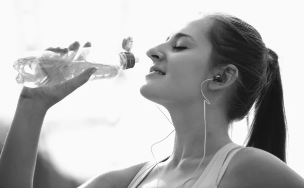 Monochrome portrait of sporty woman drinking water while jogging — Stock Photo, Image