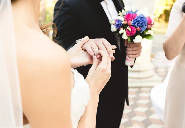 Красивая молодая невеста надевает обручальное кольцо на палец жениха — стоковое фото