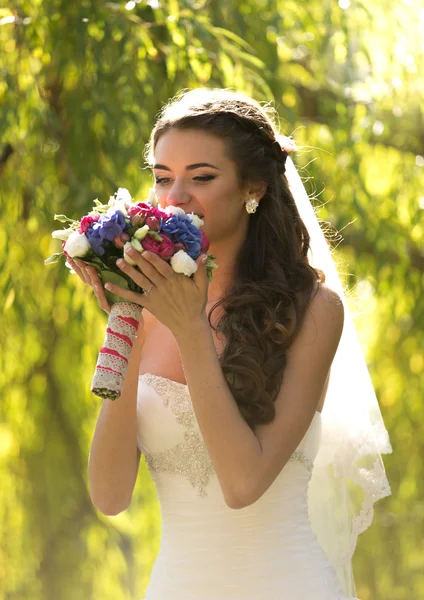 Retrato de noiva morena elegante cheirando buquê de casamento — Fotografia de Stock