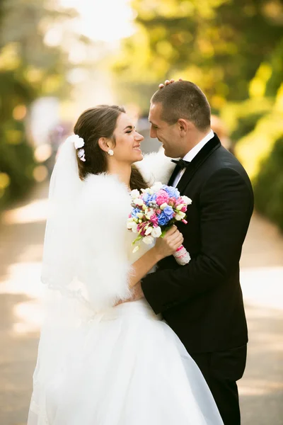 Улыбающиеся невеста и жених смотрят друг на друга в осеннем парке — стоковое фото