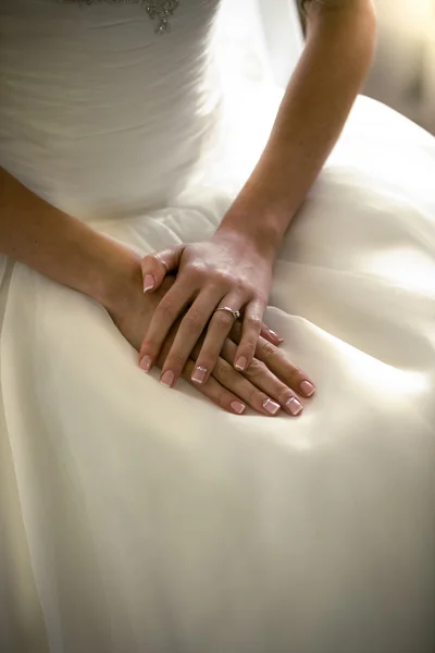 Portret ręce narzeczonych leżącego na biała suknia ślubna — Zdjęcie stockowe