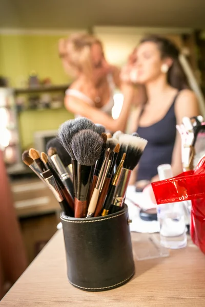 Set of professional makeup brushes against artist doing makeup — Stock Photo, Image