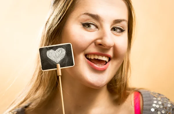 Smiling woman posing with decorative chalk boar with drawn heart — Stock Photo, Image