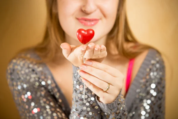 Krásná usměvavá žena držící dekorativní červené srdce na straně — Stock fotografie