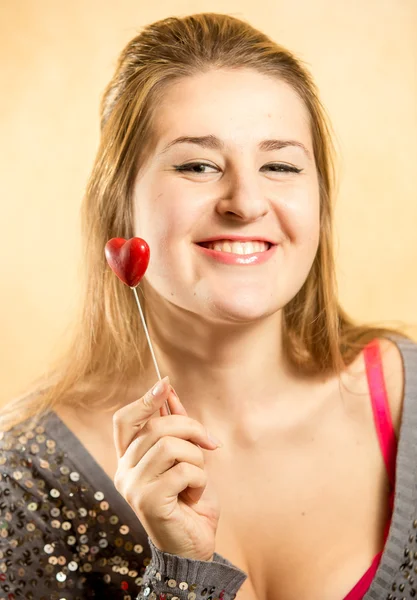 Žena s zubatými úsměv pózuje s dekorativní červené srdce — Stock fotografie