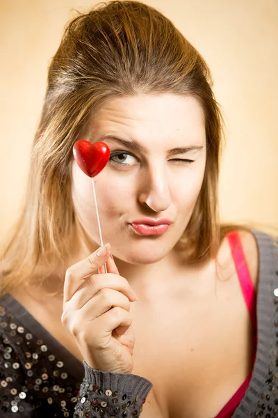Žena držící dekorativní červené srdce a při pohledu na fotoaparát — Stock fotografie