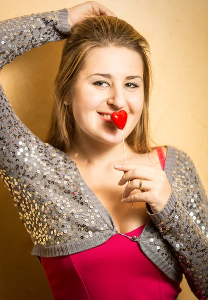 Smiling woman in dress holding decorative heart at lips — Stock Photo, Image