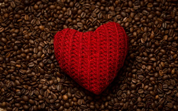 Cuore rosso lavorato a maglia sdraiato sui chicchi di caffè — Foto Stock