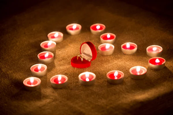 Caja con anillo de oro en el corazón hecho de velas — Foto de Stock