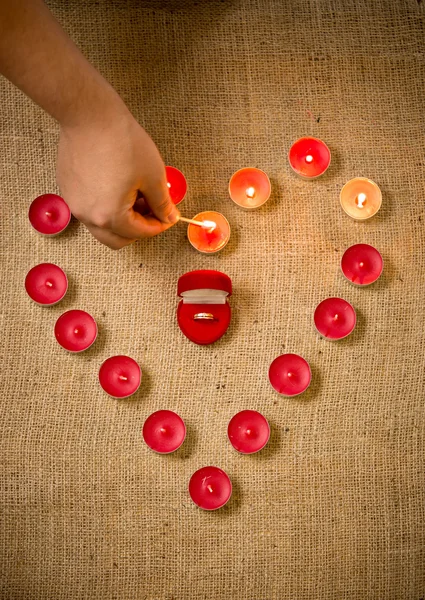 Foto de pessoa acendendo velas decorativas em torno do anel na caixa — Fotografia de Stock