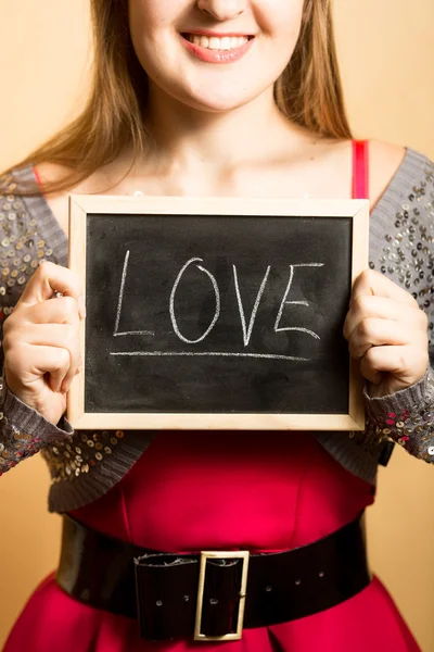 Portrait of smiling woman holding blackboard with word "Love" — Stock Photo, Image