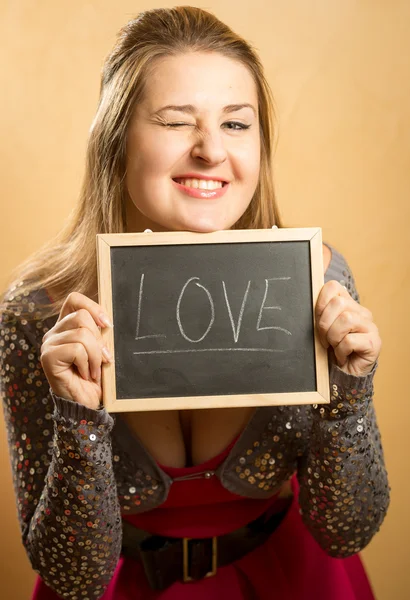 Lachende Frau posiert mit Wort "Liebe" auf Tafel geschrieben — Stockfoto