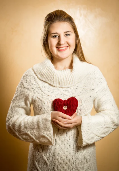 Femme souriante tenant grand coeur tricoté rouge — Photo