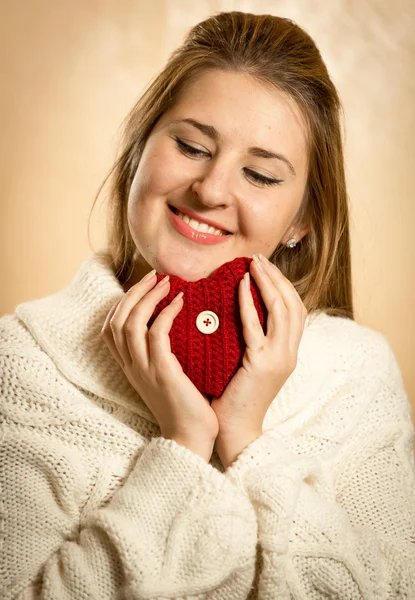 Cute blonde woman embracing red knitted heart — Stock Photo, Image