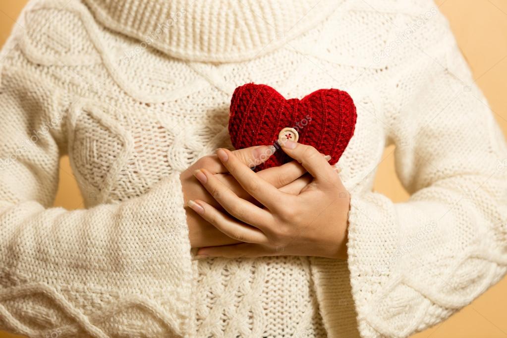 woman holding red heart at chest