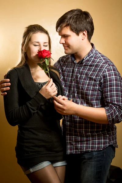 Young woman smelling red rose presented by young man — Stock Photo, Image