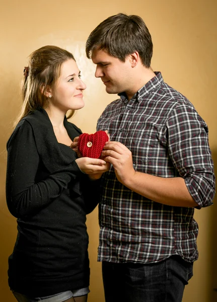 Sonriente pareja enamorada sosteniendo el corazón rojo en las manos —  Fotos de Stock