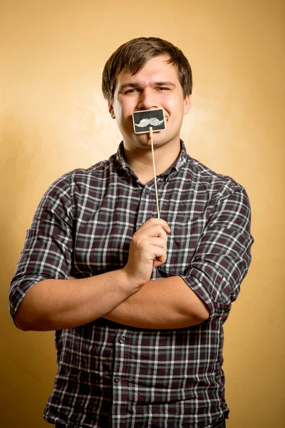 Legrační člověk drží falešný knír na klacek na ústa — Stock fotografie