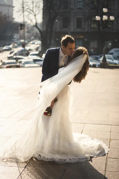 Bruid en bruidegom knuffelen op winderige dag op straat stad — Stockfoto