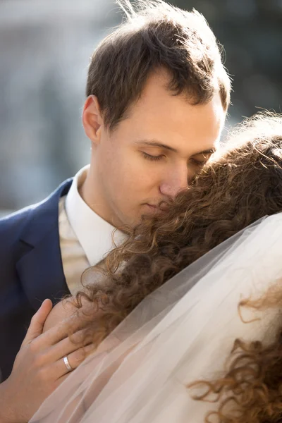 Handsome young groom hugging bride tenderly — Stock Photo, Image