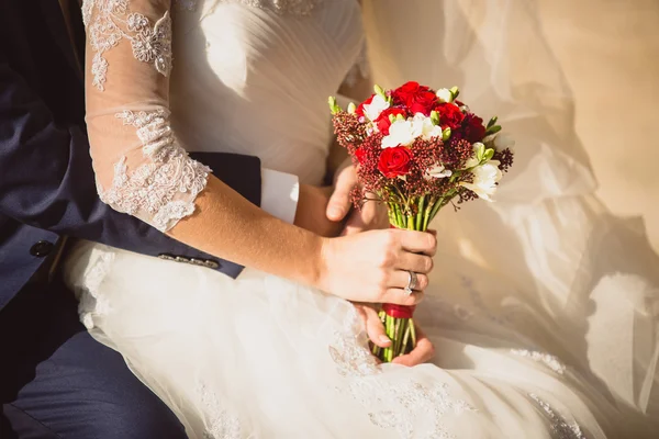 Marié étreignant mariée tenant bouquet de mariage — Photo