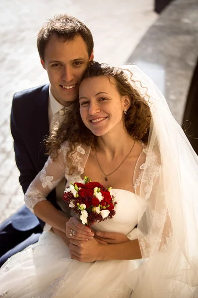 Young groom hugging smiling bride from back on street — Stock Photo, Image