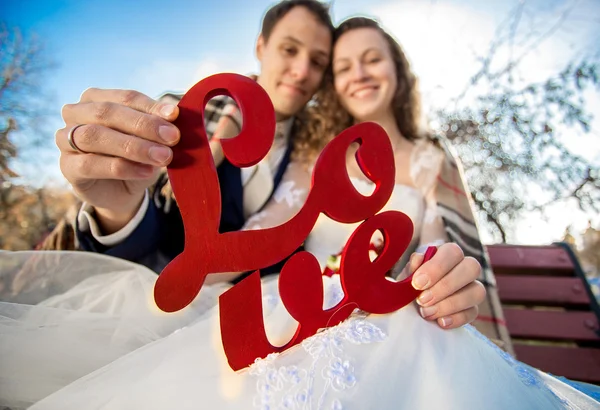 Retrato de recién casados felices sosteniendo signo de palabra de amor — Foto de Stock