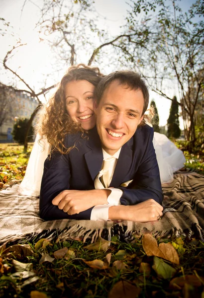 Portrait of happy bride and groom embracing on grass at park — Stock Photo, Image