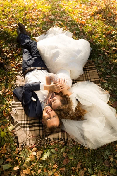 Po prostu małżeństwo leżącego na żółte listowie w parku — Zdjęcie stockowe
