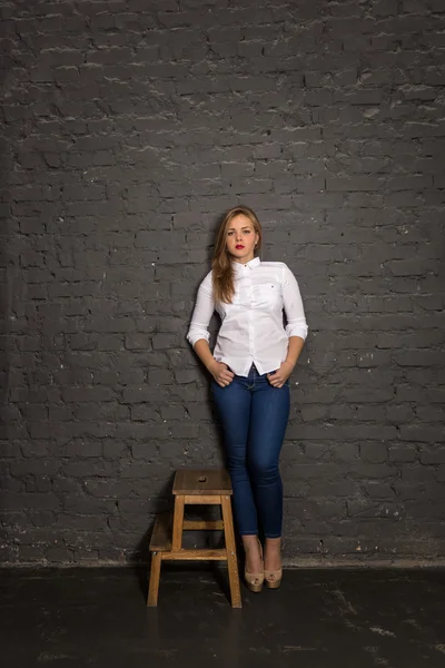 Mujer sexy en camisa y jeans apoyados en la pared de ladrillo negro —  Fotos de Stock