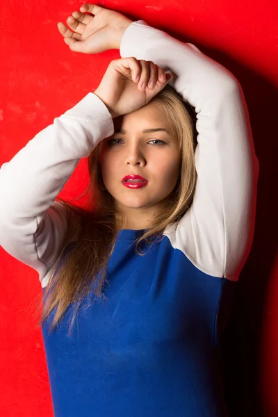 Sexy sporty blonde woman leaning against red background — Stock Photo, Image