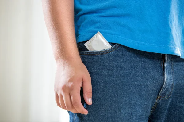 Joven en jeans con condón en el bolsillo —  Fotos de Stock