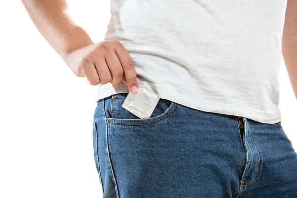 Young man putting condom in jeans pocket — Stock Photo, Image