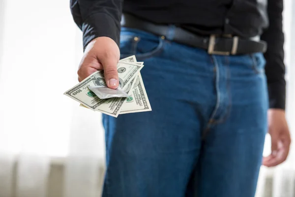 Young man holding pack of dollars and condom — Stock Photo, Image