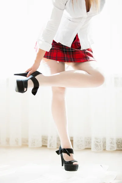 Slim woman in school uniform taking of high heels — Stock Photo, Image