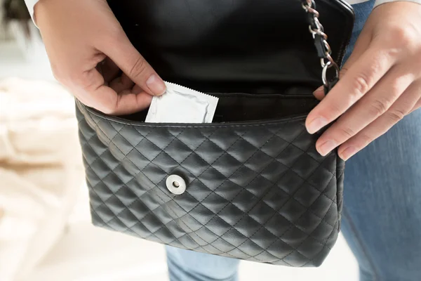 Femme prenant un préservatif emballé dans son sac à main — Photo