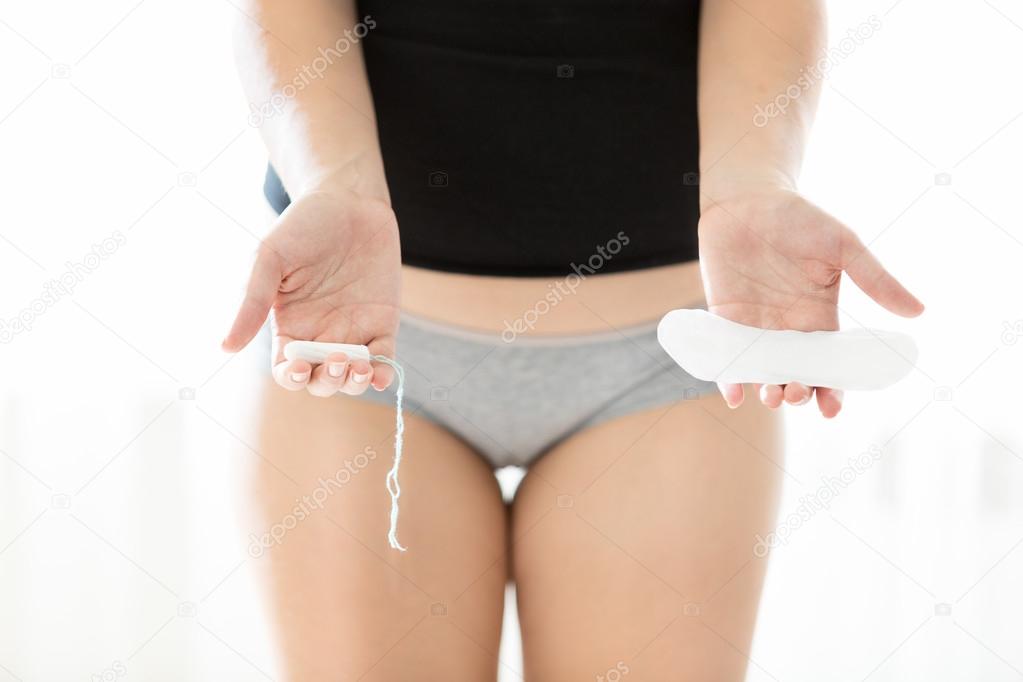 photo of young woman holding hygiene pad and tampon