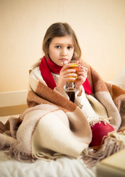 Niña enferma cubriendo a cuadros y sosteniendo la taza de té — Foto de Stock