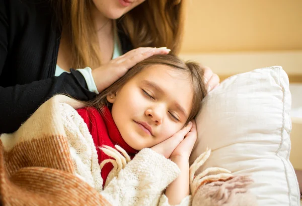 Madre che tiene la mano sulla testa delle figlie addormentate — Foto Stock