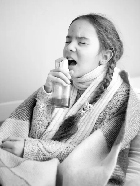 Retrato monocorme de una niña en la cama usando aerosol para la garganta —  Fotos de Stock