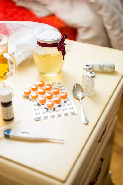 Photo of pills and medicines lying on table next to bed — Stock Photo, Image