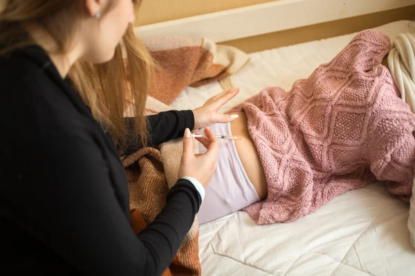 Woman doing injection in girls bottom lying on bed — Stock Photo, Image