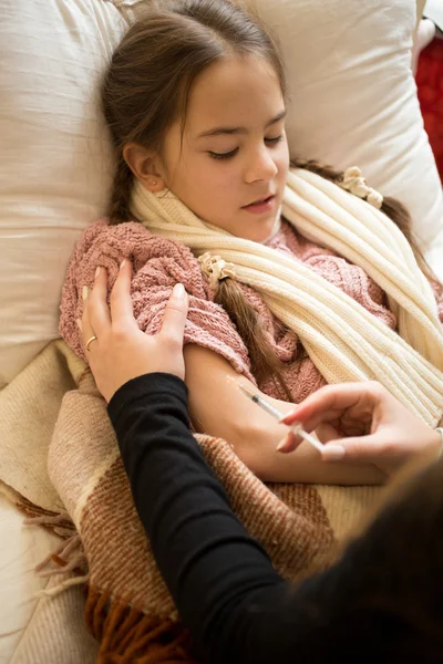 Vrouw doen injectie in meisjes hand liggend in bed — Stockfoto