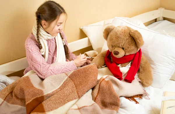 Meisje op bed zitten en doen injectie bruin teddy bear — Stockfoto