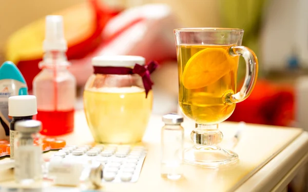 Closeup shot of tea and medicines on table next to bed — Stock Photo, Image