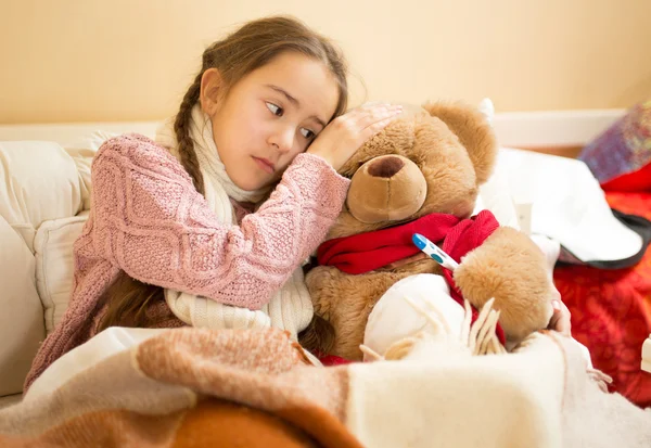 Little girl hold hand on teddy bears head and measuring temperat — Stock Photo, Image