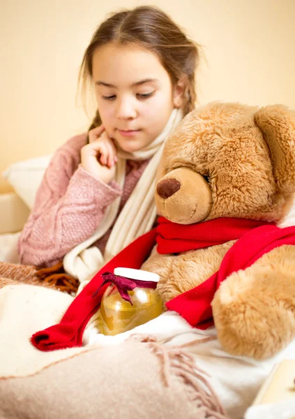 Menina deitada na cama com ursinho de pelúcia com mel jar — Fotografia de Stock