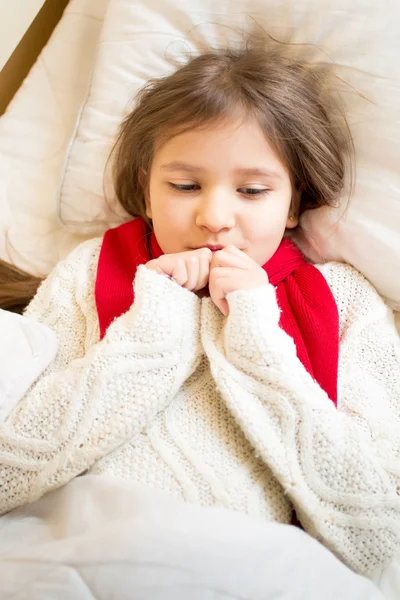 Porträt eines kleinen Mädchens im Pullover, das unter einer Decke im Bett liegt — Stockfoto