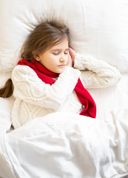 Girl in sweater and scarf lying sleeping at bed — Stock Photo, Image