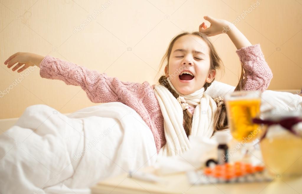 little girl with flu yawning in bed at morning